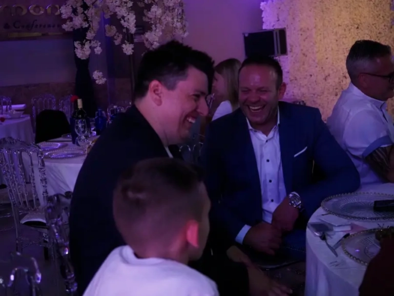 Mentalist Florian Dolar lacht mit einem Gast am festlich gedeckten Tisch während einer Hochzeitsfeier